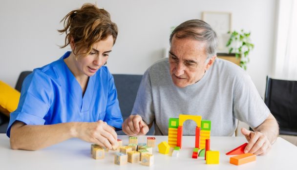 Female,Caregiver,And,Senior,Man,Playing,Wooden,Shape,Puzzles,Game