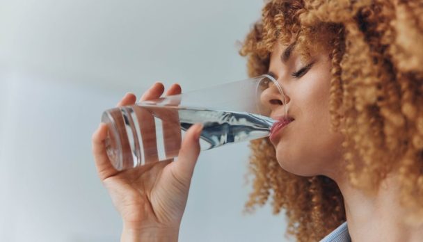 Curly,Haired,Woman,Drinking,Water,From,A,Glass,With,A