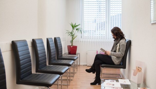 Young,Patient,Reading,A,Magazine,In,The,Doctorâ??s,Waiting,Room